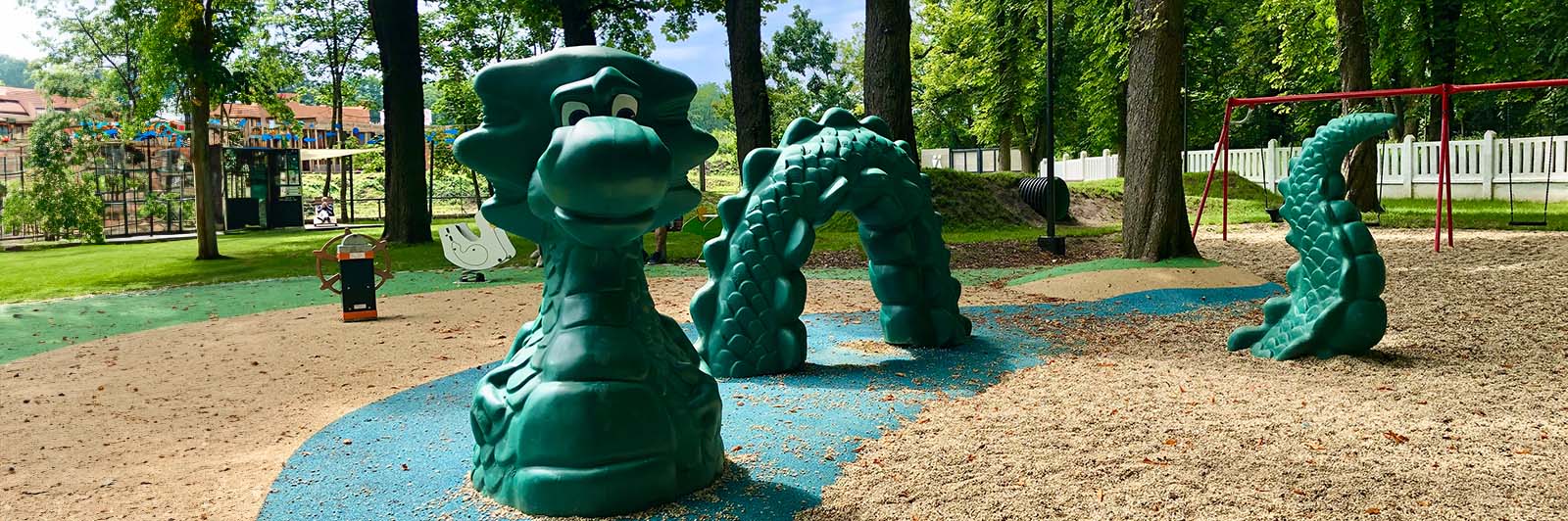 A large play sculpture shaped like a dragon, coming in and out of the ground so children can climb and play on it.